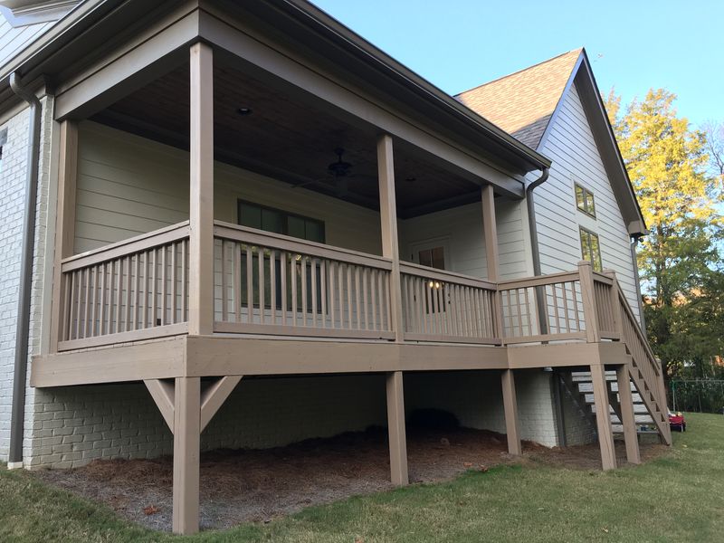 Covered back porch with tan painted posts and railings