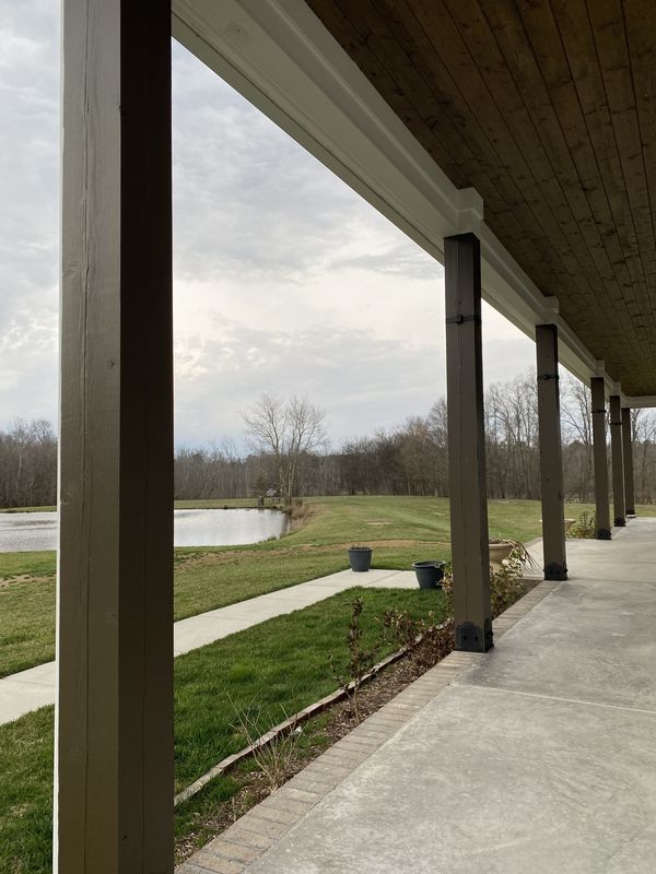 Long covered porch with dark stained posts and a wood plank ceiling
